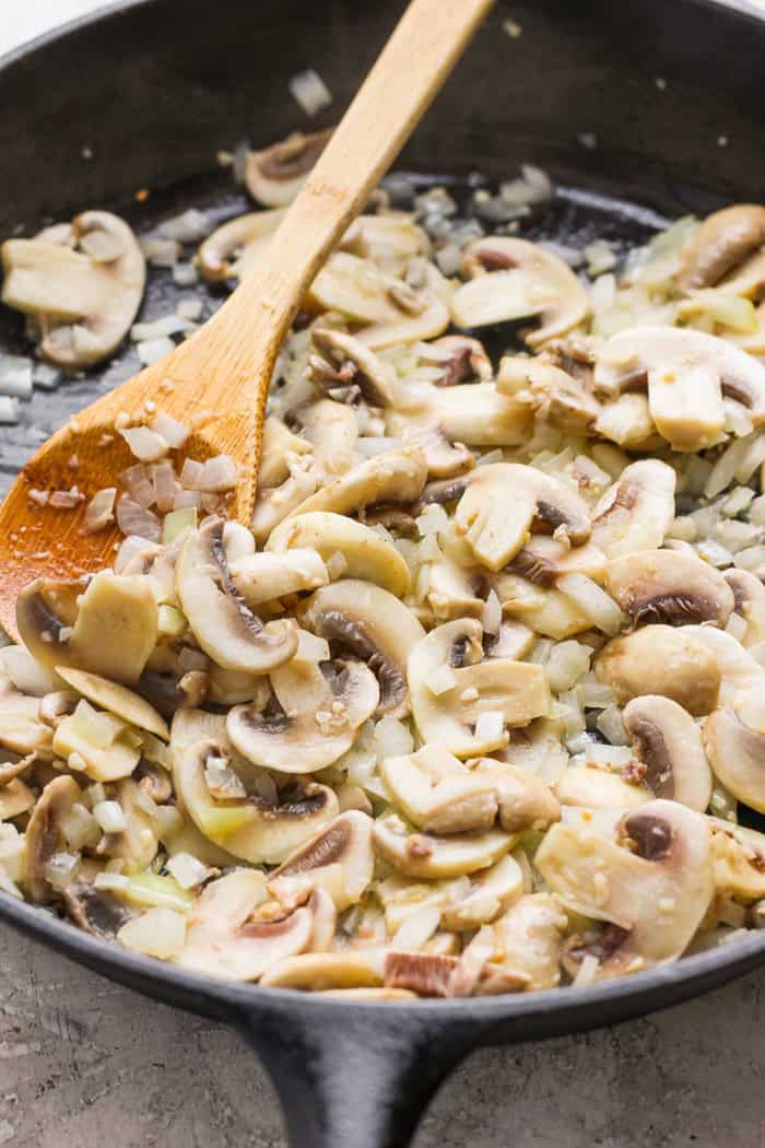 My easy made-from-scratch Tater Tot Hotdish is classic Minnesota comfort food — but fear not, I also share a canned soup version too! Cooking mushrooms and onions in skillet for tater tot hotdish