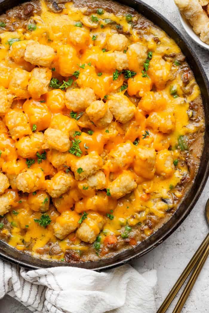 My easy made-from-scratch Tater Tot Hotdish is classic Minnesota comfort food — but fear not, I also share a canned soup version too! Overhead view of tater tot hotdish in cast iron skillet