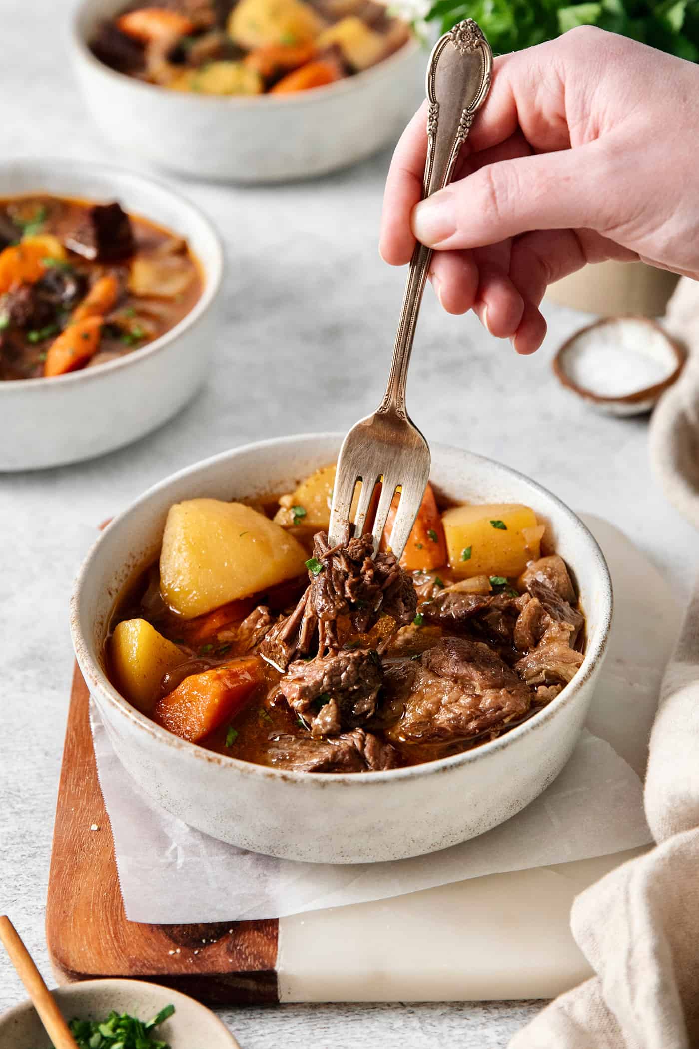 Slow Cooker Hungarian Goulash loaded with chunks of tender, melt-in-your-mouth beef and vegetables. Authentic, easy comfort food at its best! A hand holding a spoon in a bowl of goulash