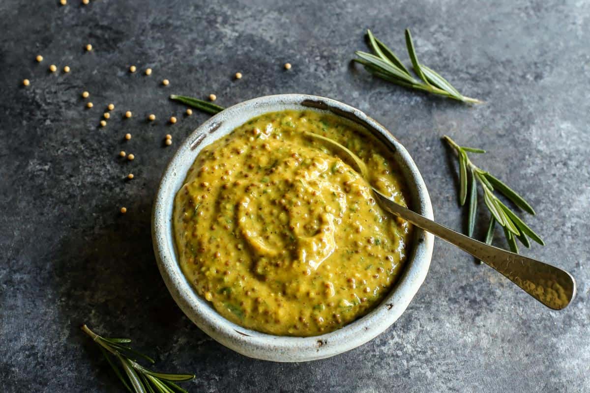 This pork loin roast recipe is juicy and tender, slathered with a savory mustard mixture and oven-roasted for a satisfying, easy pork dinner. Overhead view of homemade mustard sauce in a bowl with a spoon.