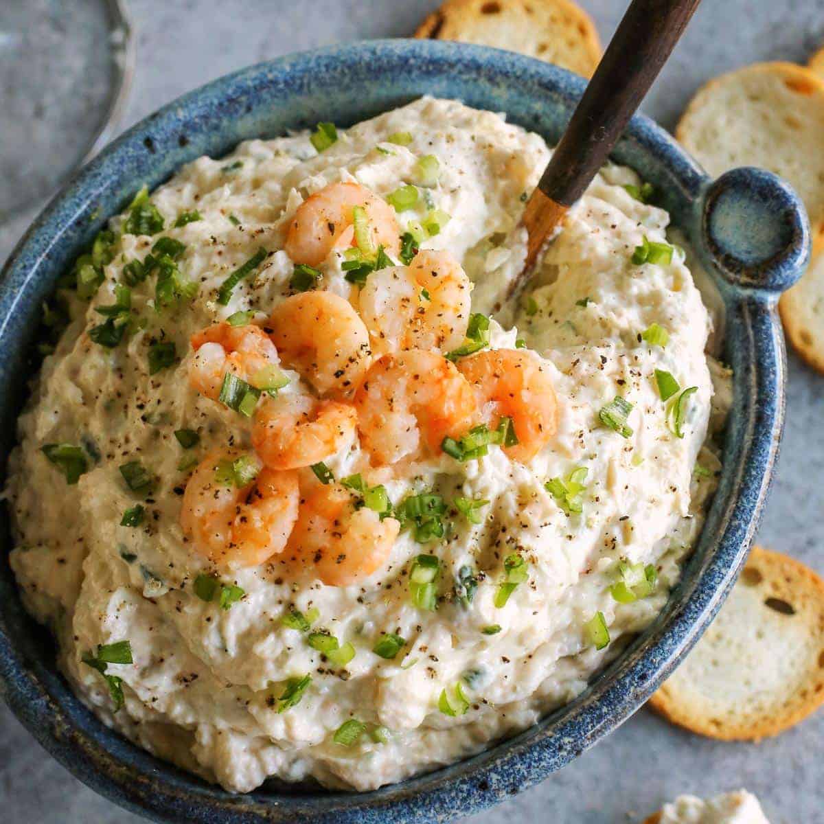 This shrimp dip recipe is an easy appetizer, made with just a few ingredients. It's thick and creamy, and full of tender, juicy shrimp! Blue bowl of dip with shrimp.
