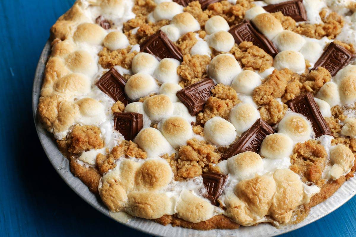 Gooey, chocolatey, and utterly delicious, this S'mores Pie allows you to enjoy the flavors of the classic summertime treat any time of the year. No campfire required! S'mores Pie on blue table