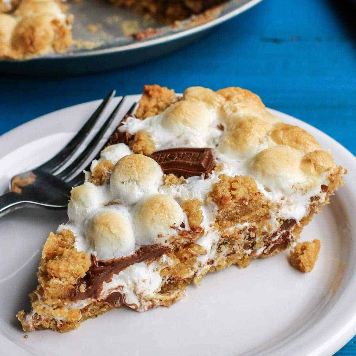 Gooey, chocolatey, and utterly delicious, this S'mores Pie allows you to enjoy the flavors of the classic summertime treat any time of the year. No campfire required! S'mores Pie slice with a fork