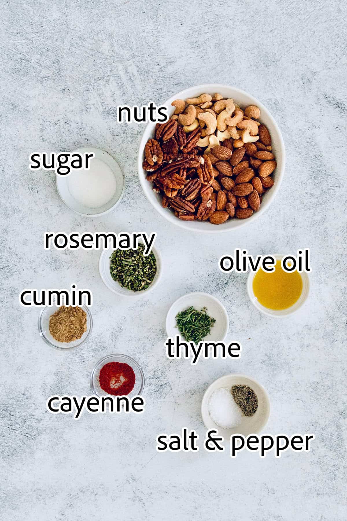 This homemade, baked spiced nuts recipe with herb-infused olive oil, cumin, spicy cayenne, and sugar is an easy holiday appetizer. Labeled ingredients for making my spiced nuts recipe.