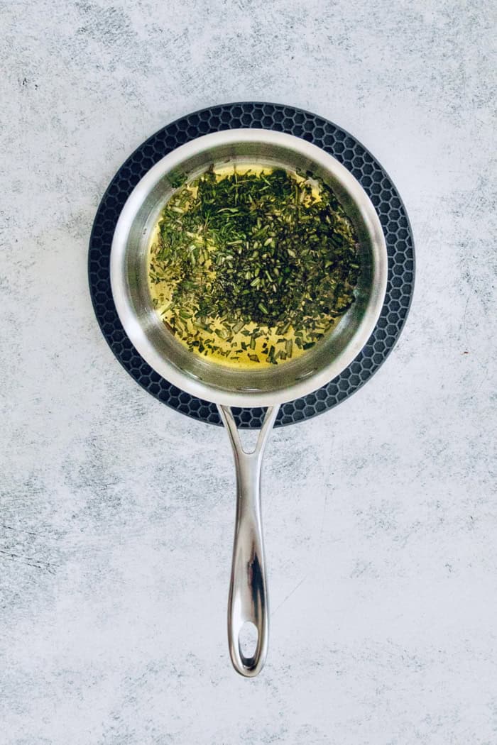 This homemade, baked spiced nuts recipe with herb-infused olive oil, cumin, spicy cayenne, and sugar is an easy holiday appetizer. Infusing the olive oil with rosemary and thyme in a pot.