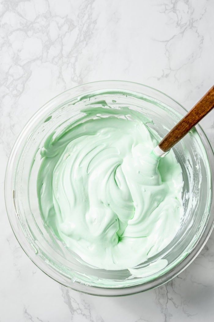 This Grasshopper Cake has layers of moist mint cake, chocolate fudge, and creme de menthe-infused whipped cream. So easy too! Mint Cool Whip in bowl