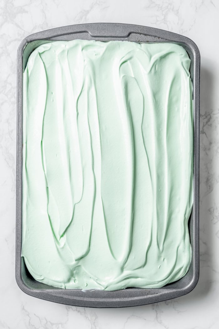 This Grasshopper Cake has layers of moist mint cake, chocolate fudge, and creme de menthe-infused whipped cream. So easy too! Grasshopper cake in pan before adding Andes mints