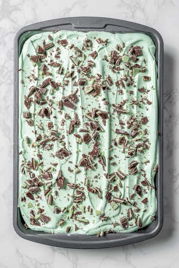 This Grasshopper Cake has layers of moist mint cake, chocolate fudge, and creme de menthe-infused whipped cream. So easy too! Grasshopper cake in pan before slicing