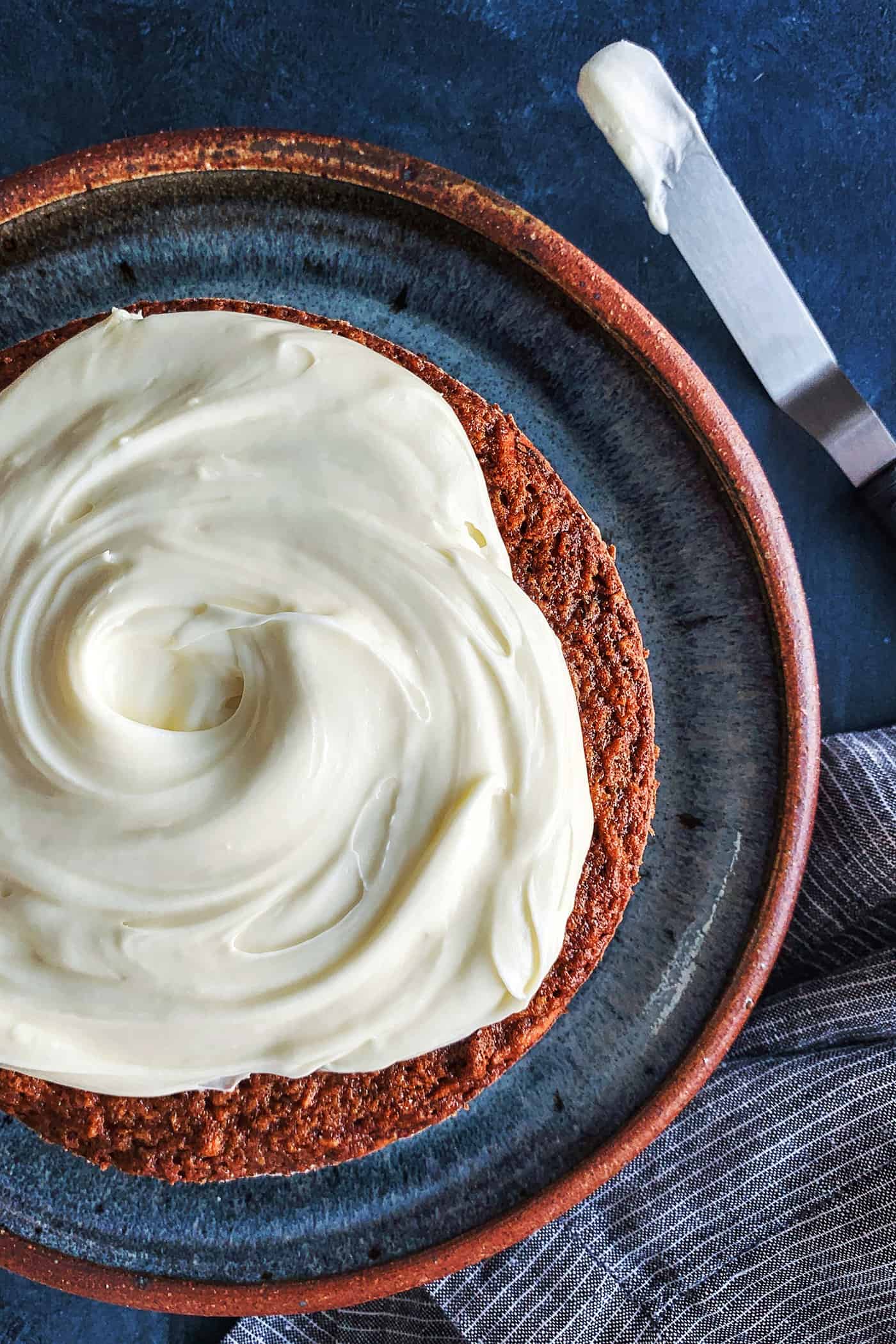 This classic carrot cake recipe is moist, perfectly spiced, and baked in a single layer, topped with creamy homemade cream cheese frosting. Cream cheese icing spread on top of carrot cake
