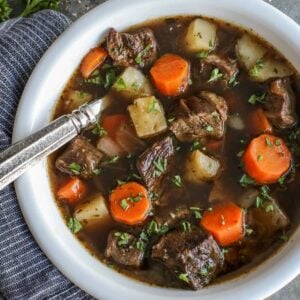 Overhead view of Irish beef stew with potatoes and carrots in a bowl with a spoon.