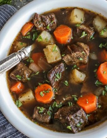 Overhead view of Irish beef stew with potatoes and carrots in a bowl with a spoon.