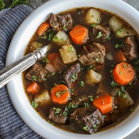 Overhead view of Irish beef stew with potatoes and carrots in a bowl with a spoon.