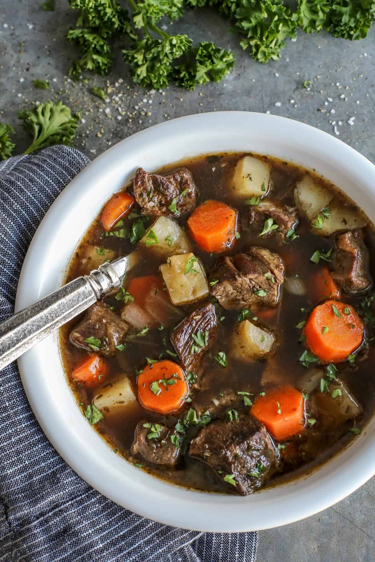 This traditional Irish beef stew is extra hearty, with tender beef and vegetables simmered in a rich beef broth with Irish Guinness beer. Overhead view of Irish beef stew with potatoes and carrots in a bowl with a spoon.