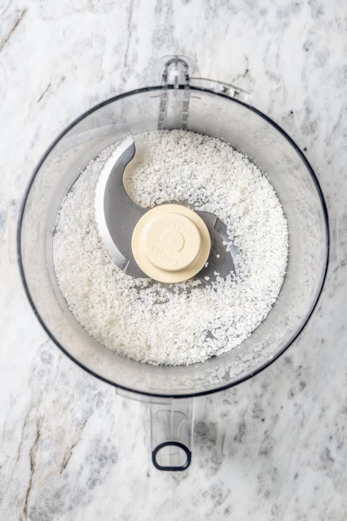 These coconut cupcakes are moist and full of coconut flavor — and just wait until you sink your teeth into the coconut buttercream frosting! Overhead view of shredded coconut in food processor