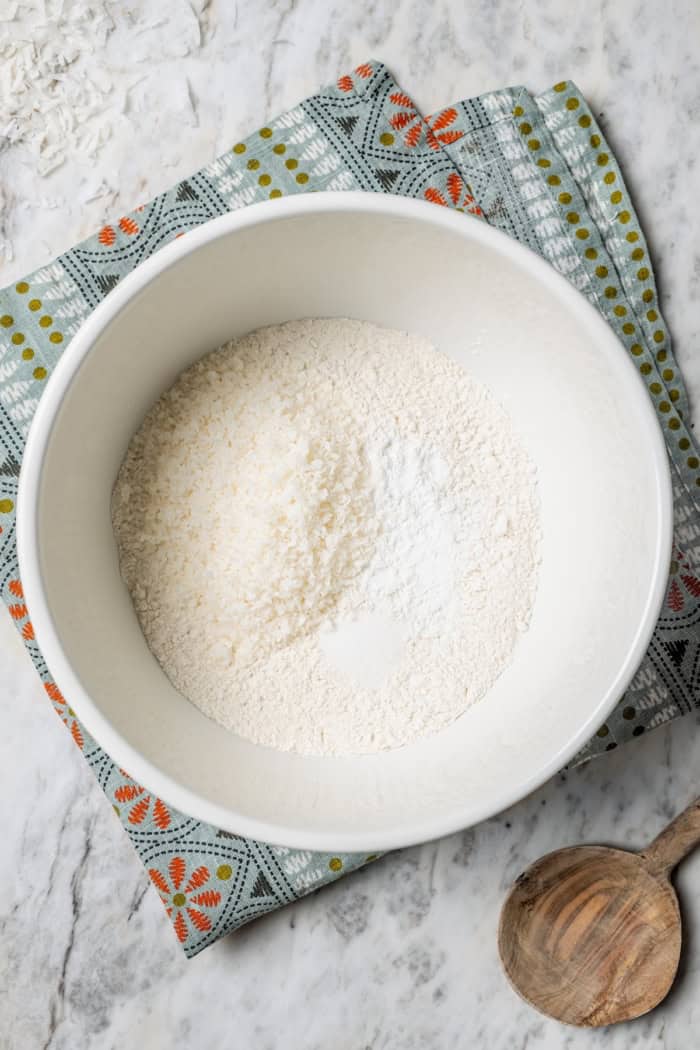 These coconut cupcakes are moist and full of coconut flavor — and just wait until you sink your teeth into the coconut buttercream frosting! Overhead view of dry ingredients in bowl for coconut cupcakes