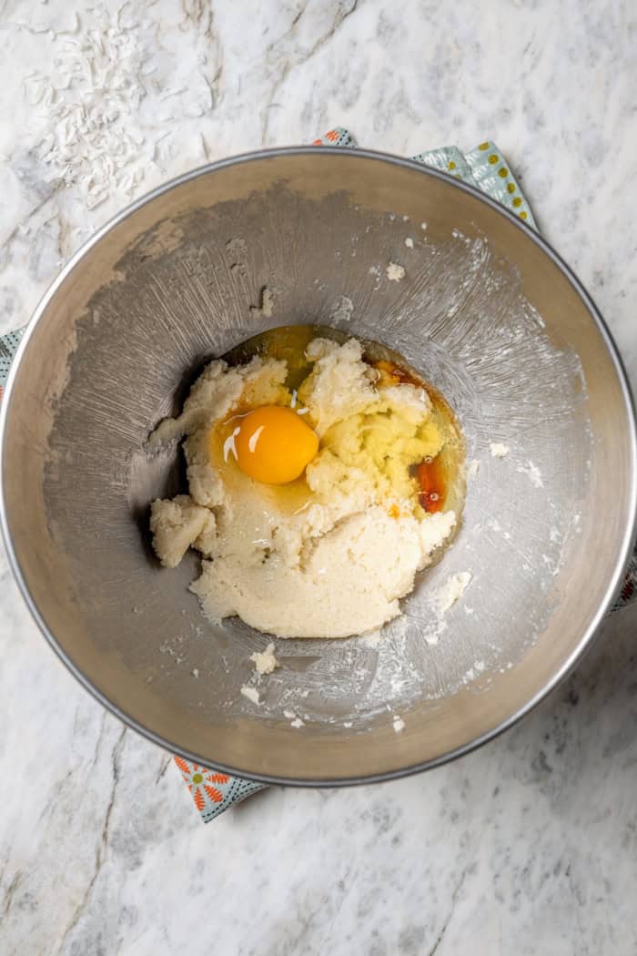 These coconut cupcakes are moist and full of coconut flavor — and just wait until you sink your teeth into the coconut buttercream frosting! Overhead view of egg added to wet ingredients in bowl