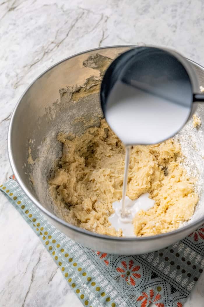 These coconut cupcakes are moist and full of coconut flavor — and just wait until you sink your teeth into the coconut buttercream frosting! Pouring coconut milk into bowl of batter