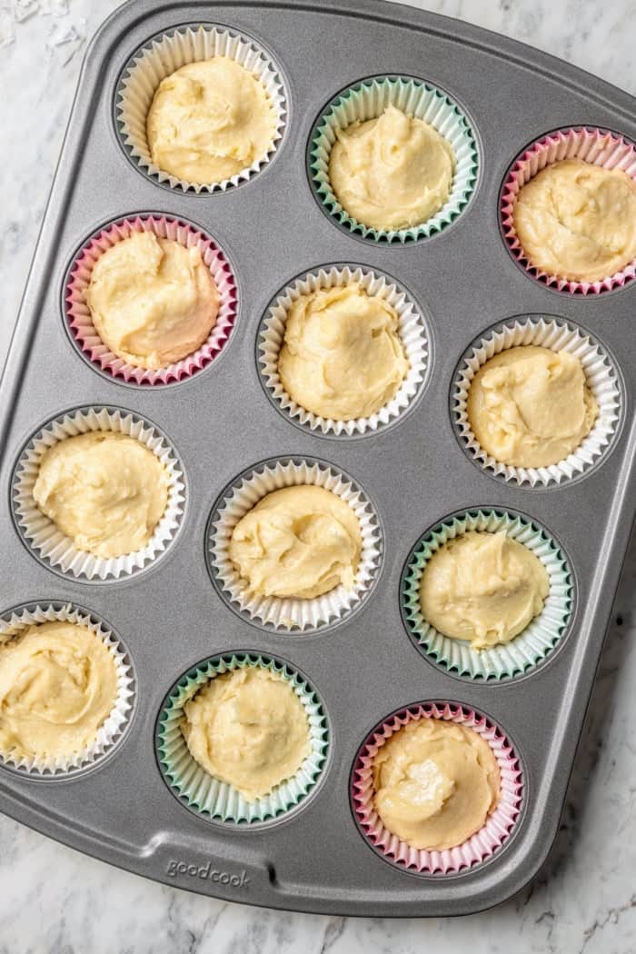 These coconut cupcakes are moist and full of coconut flavor — and just wait until you sink your teeth into the coconut buttercream frosting! Overhead view of coconut cupcake batter in pan