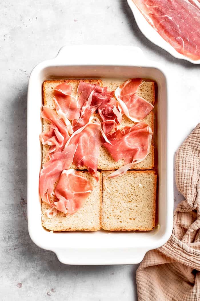 Prosciutto added over bread layer in casserole dish