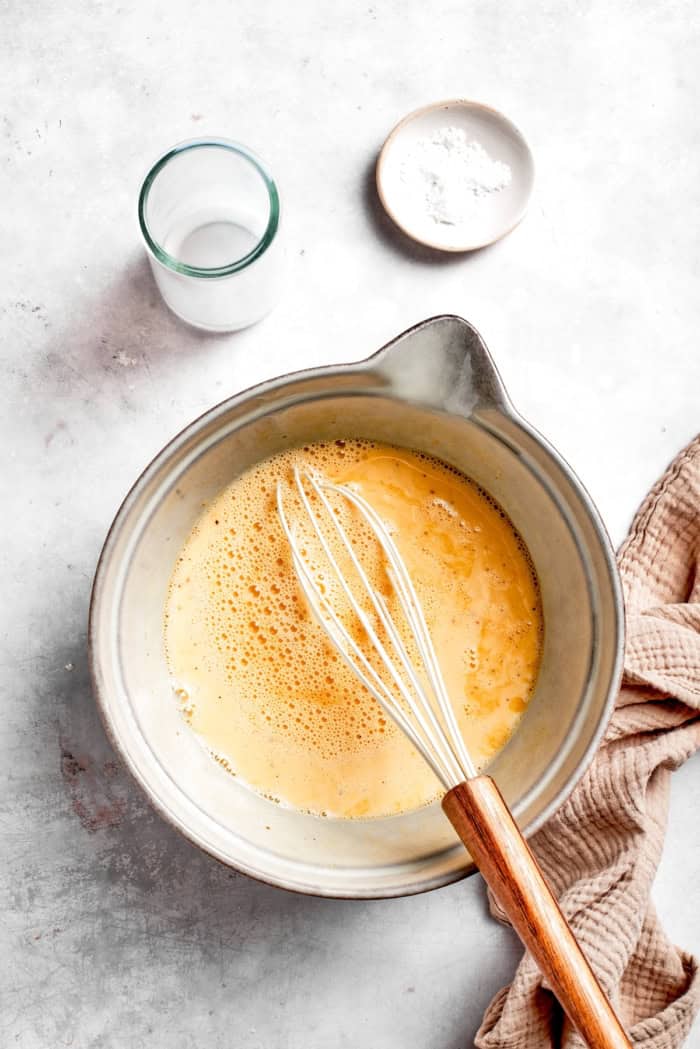 Overhead view of egg mixture in bowl with whisk