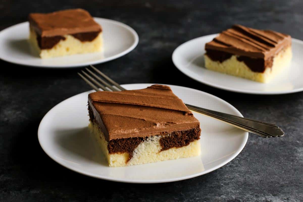 This Easy Marble Cake Recipe features a moist chocolate and vanilla sheet cake slathered with a rich & creamy chocolate buttercream frosting. pieces of marble cake on plates