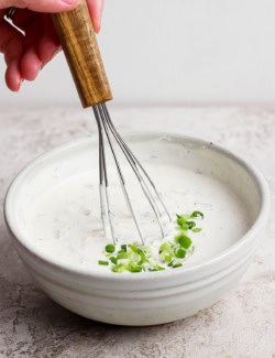 Whisking buttermilk ranch dressing in bowl