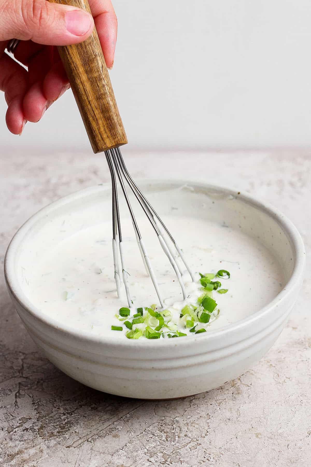 This Homemade Buttermilk Ranch Dressing recipe is fresh, creamy and tangy, with a few tweaks that really make the flavor pop. So easy too! Whisking buttermilk ranch dressing in bowl