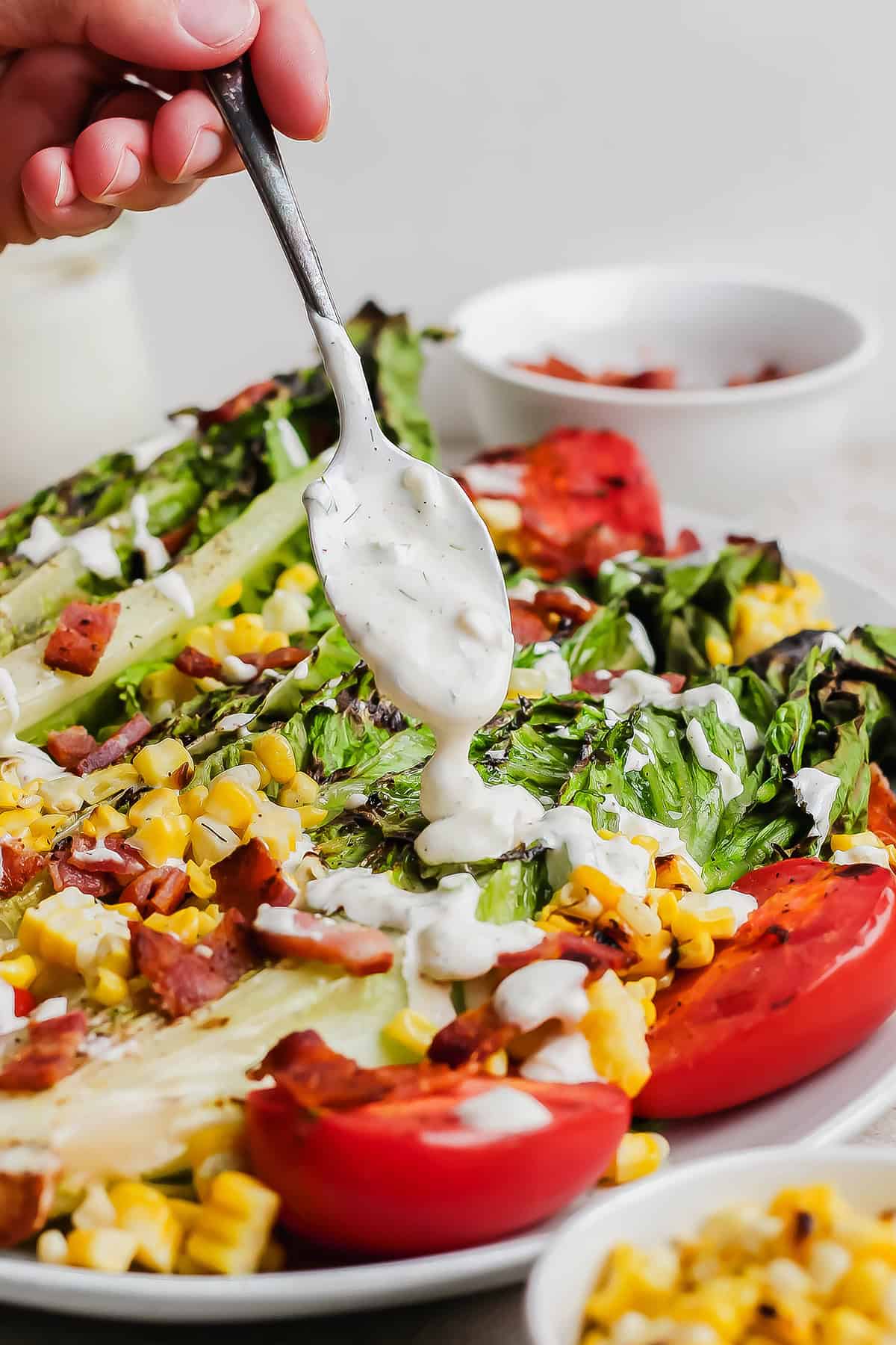 This Homemade Buttermilk Ranch Dressing recipe is fresh, creamy and tangy, with a few tweaks that really make the flavor pop. So easy too! Spooning buttermilk ranch dressing over salad on plate