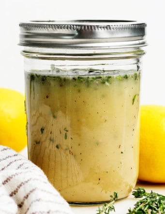 Homemade lemon vinaigrette with fresh herbs in jar