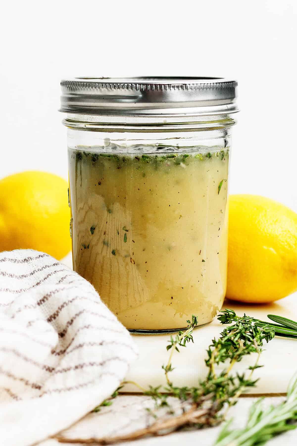Homemade lemon vinaigrette with fresh herbs in jar