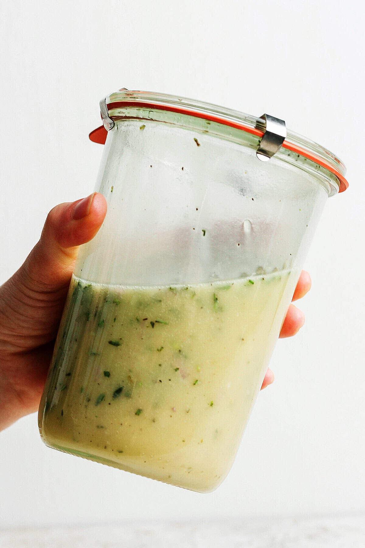 Hand holding jar with emulsified lemon vinaigrette