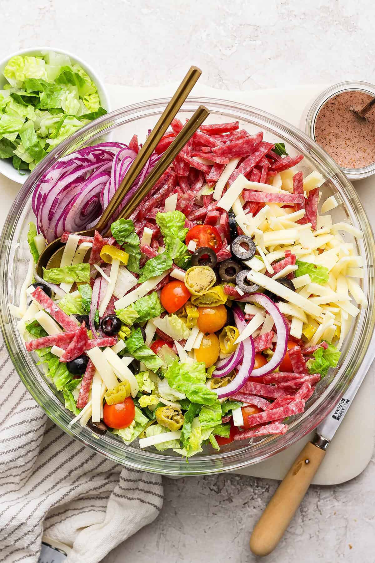This Italian Chopped Salad is loaded with fresh veggies, salami, provolone, pepperoncini, and olives for a flavorful, satisfying meal! Overhead view of Italian chopped salad in glass bowl