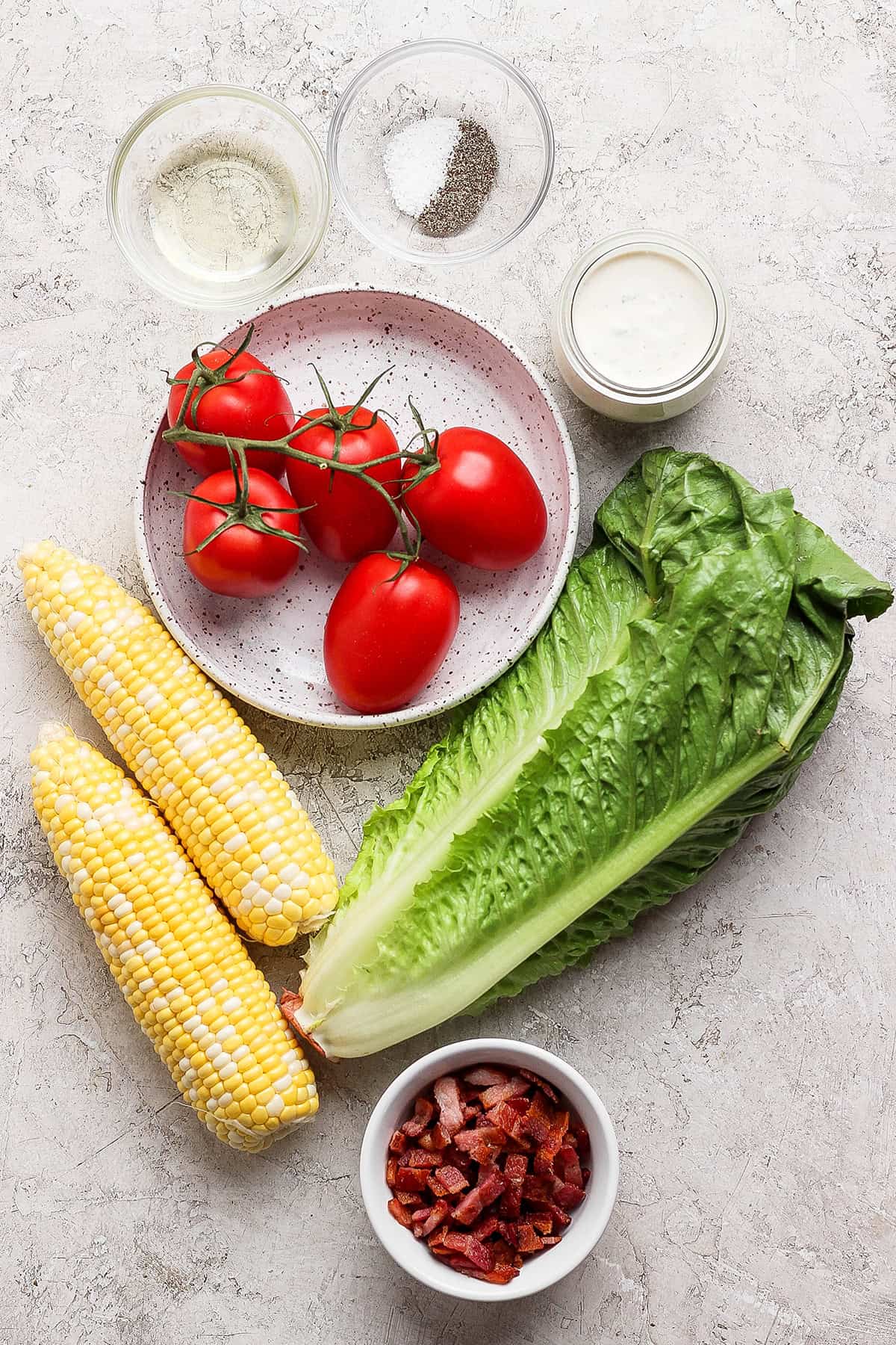 This smoky Grilled Romaine Salad is simple and summery, with tomatoes, sweet corn, crispy bacon and homemade buttermilk ranch dressing. Yum! Overhead view of ingredients for grilled romaine salad