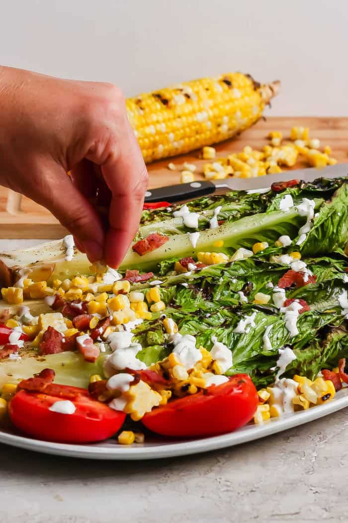 This smoky Grilled Romaine Salad is simple and summery, with tomatoes, sweet corn, crispy bacon and homemade buttermilk ranch dressing. Yum! Sprinkling bacon onto grilled romaine salad