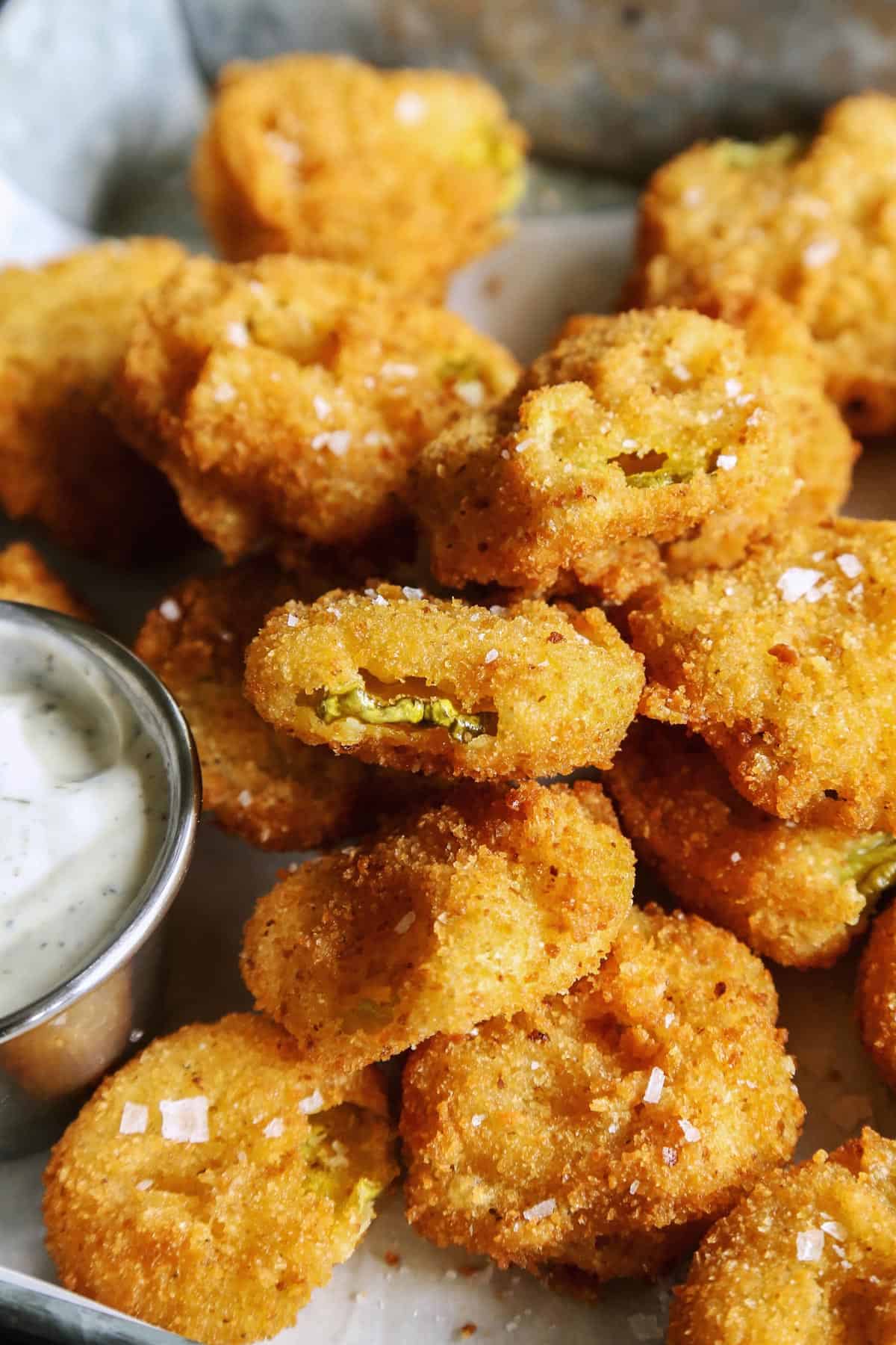 Enjoy your favorite fair food at home with these easy Fried Pickles. Dill pickles are dipped in a perfectly seasoned batter and quickly fried. fried pickles on tray with ranch dip