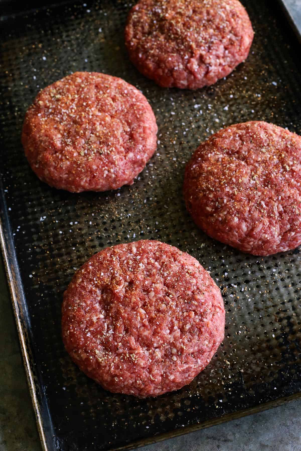 A Juicy Lucy burger is a juicy patty stuffed with molten, melty cheese. Served on a low-carb lettuce wrap or bun with your favorite toppings! Juicy Lucy burgers on a sheet pan, before grilling