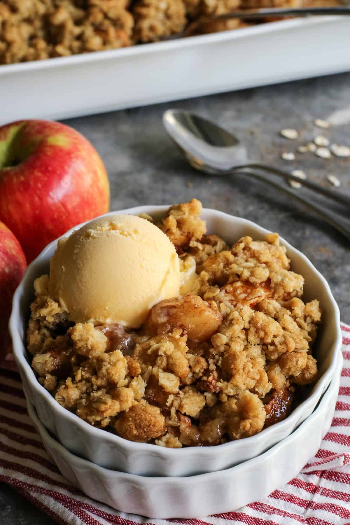 An easy apple crisp recipe with delicious apple filling and a crispy old-fashioned buttery oats topping. It's one of the best apple desserts! homemade apple crisp in a white dish with a scoop of vanilla ice cream