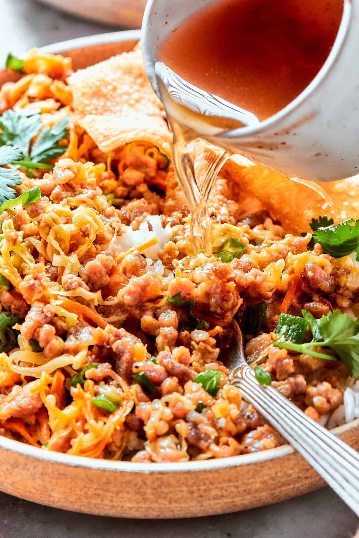 Pouring sauce into egg roll in a bowl