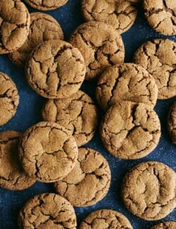 a bunch of ginger molasses cookies on a dark blue background