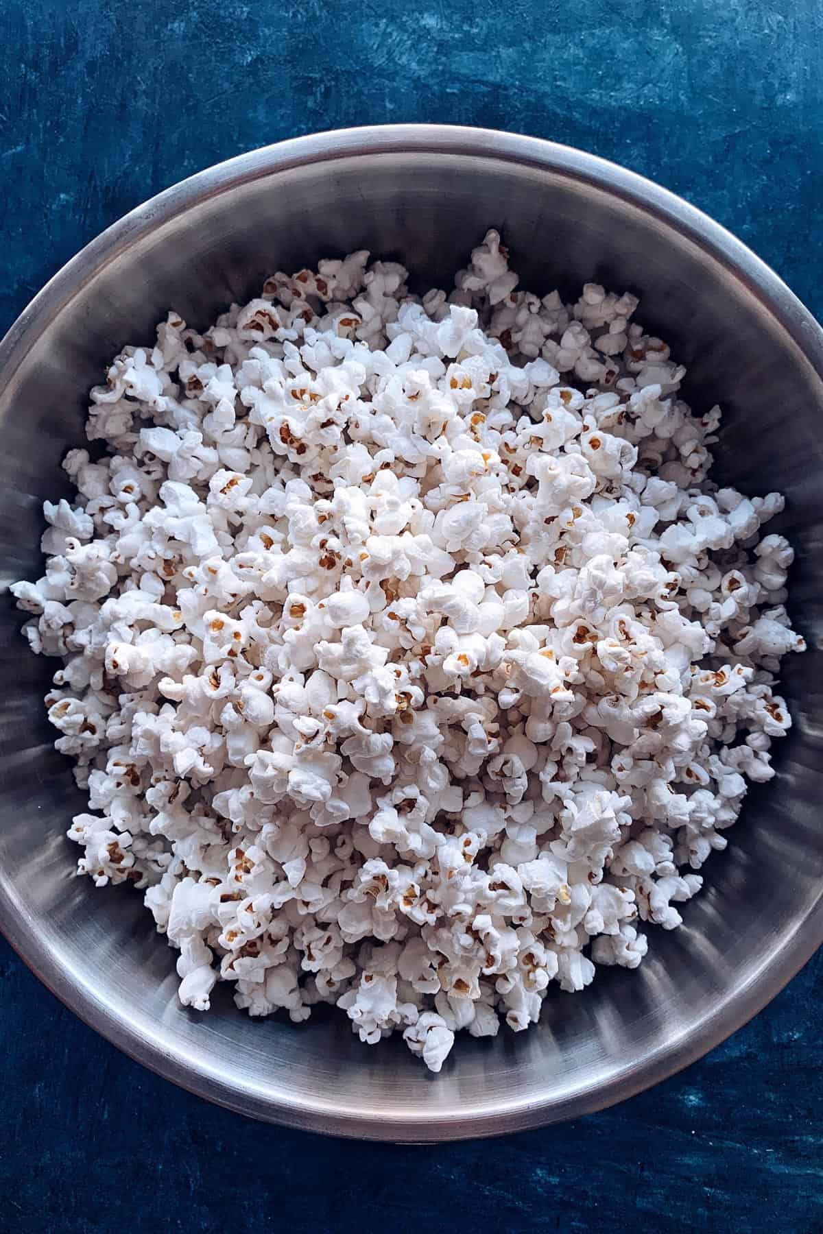 This baked caramel corn is the BEST homemade caramel popcorn recipe! It's crispy, sweet, buttery perfection. Great for gifting and snacking! Popcorn in large stainless steel bowl.