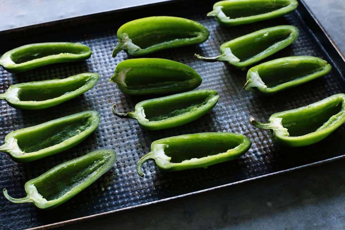 With Italian sausage, cream cheese, Parmesan, and mozzarella, these easy stuffed jalapeños are extra cheesy with the perfect amount of heat! jalapeno pepper halves on a pan