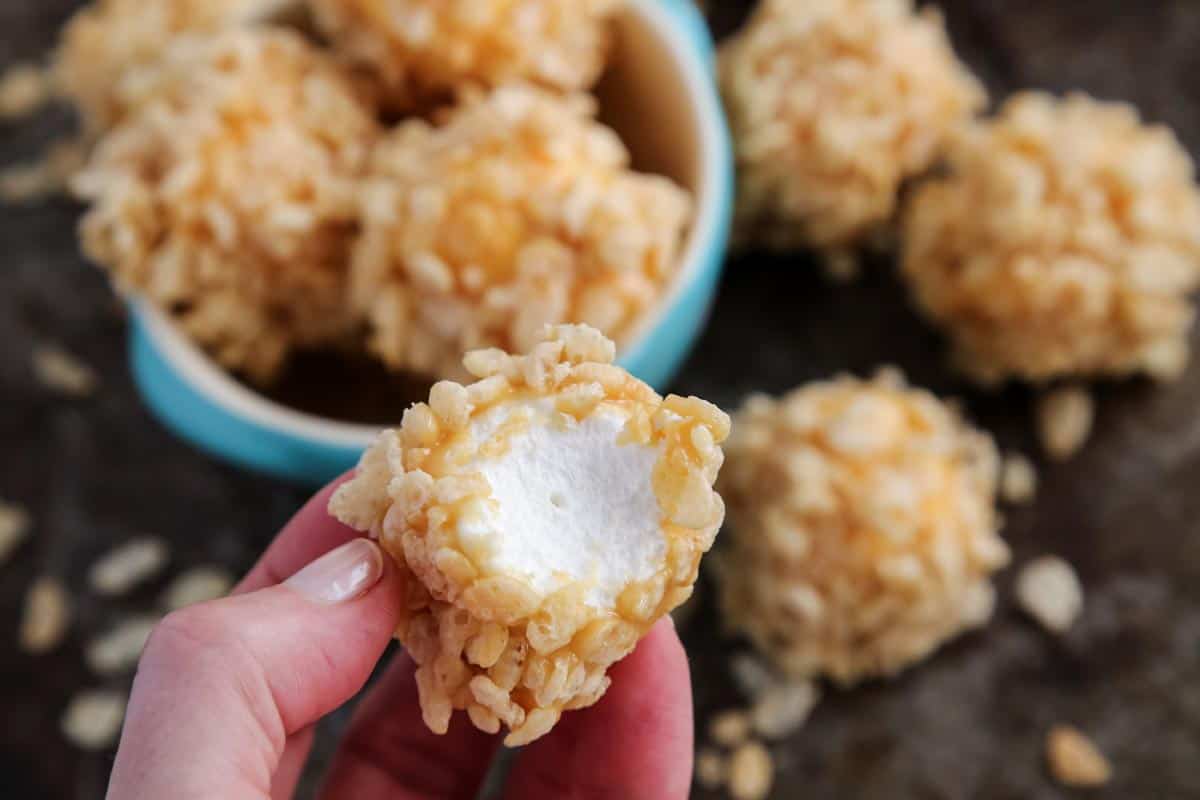 a marshmallow dipped in caramel and coated with crispy rice cereal, bitten in half