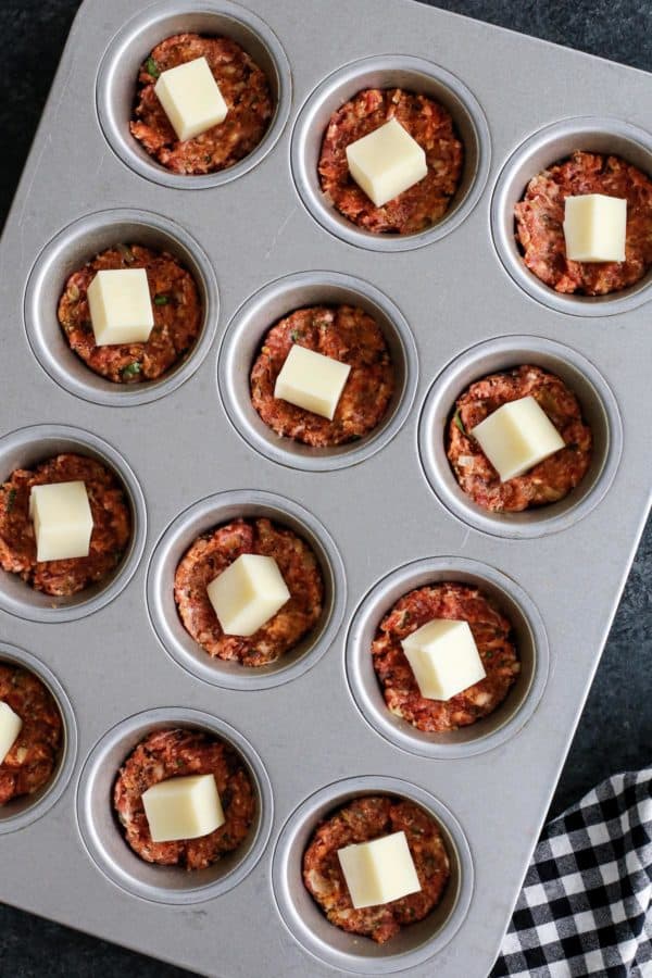 Italian Meatloaf Muffins turns your favorite meatloaf into muffins with gooey mozzarella cheese centers and savory herbs. Meatloaf mixture and mozzarella cheese in a muffin tin.