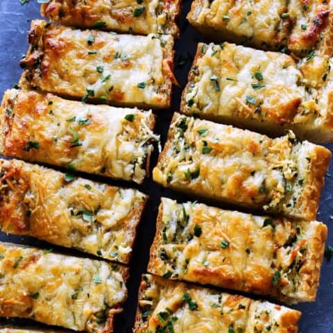 Overhead view of cheesy garlic bread cut into slices.