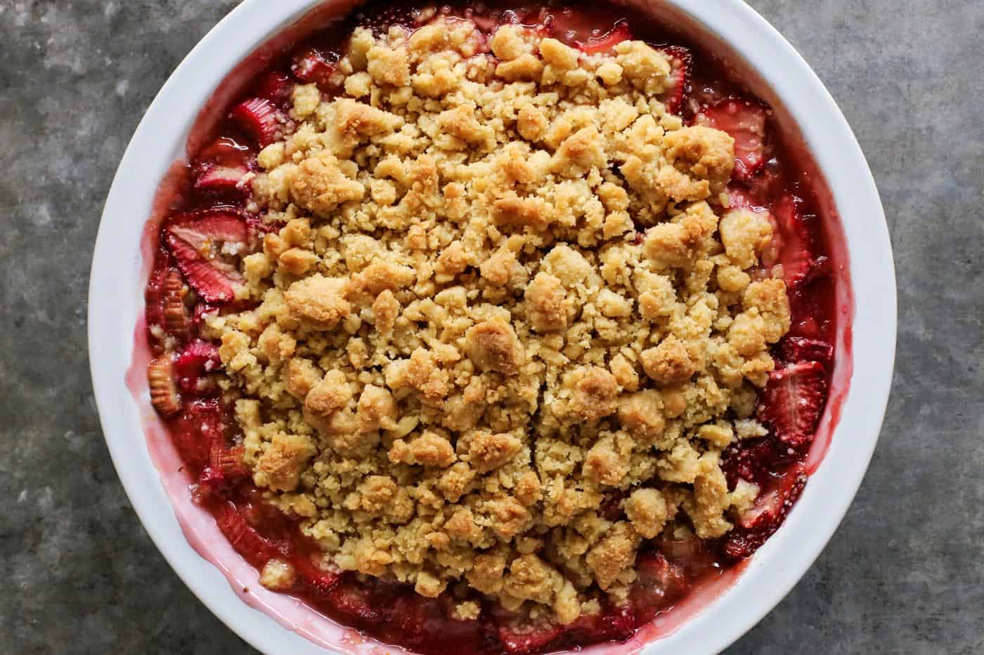 Strawberry Rhubarb Crumble is an easy dessert recipe with a sweet-tart, jammy fruit filling plus a buttery, crispy topping. strawberry rhubarb filling plus a crunchy, buttery crumble in a white pie plate