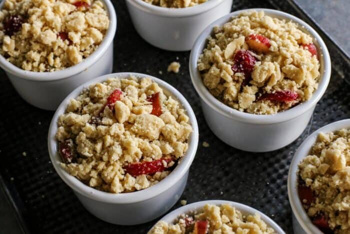 Strawberry Rhubarb Crumble is an easy dessert recipe with a sweet-tart, jammy fruit filling plus a buttery, crispy topping. ramekins of rhubarb and strawberry crumble, ready to go into the oven