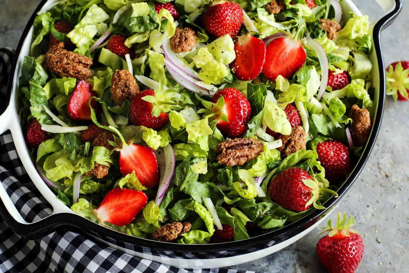 This strawberry salad with red wine vinaigrette has Monterey Jack cheese and ridiculously crunchy candied pecans. It's a crowd-pleaser! strawberry salad in a large white bowl