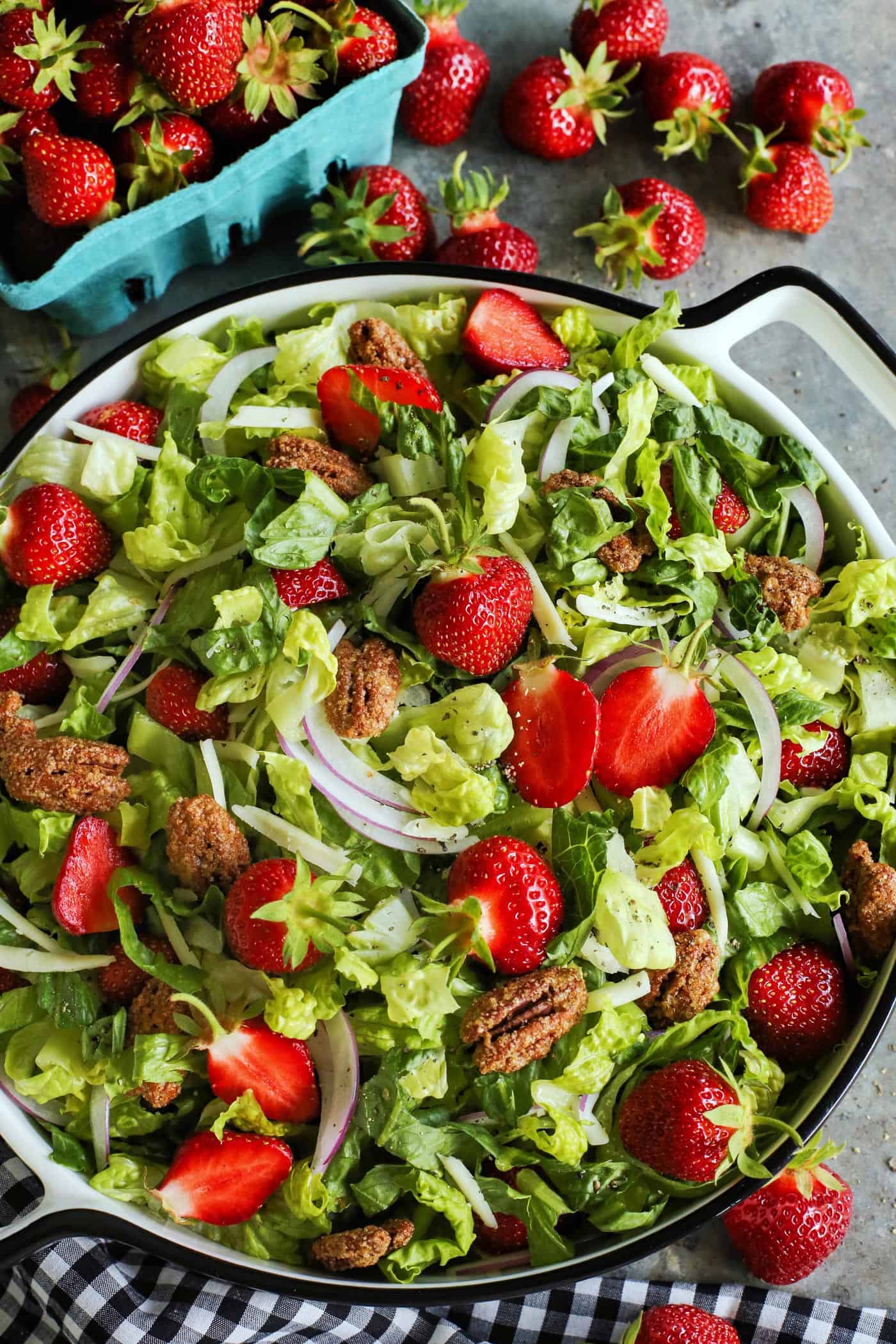 This strawberry salad with red wine vinaigrette has Monterey Jack cheese and ridiculously crunchy candied pecans. It's a crowd-pleaser! a box of ripe strawberries and strawberry salad in a large bowl