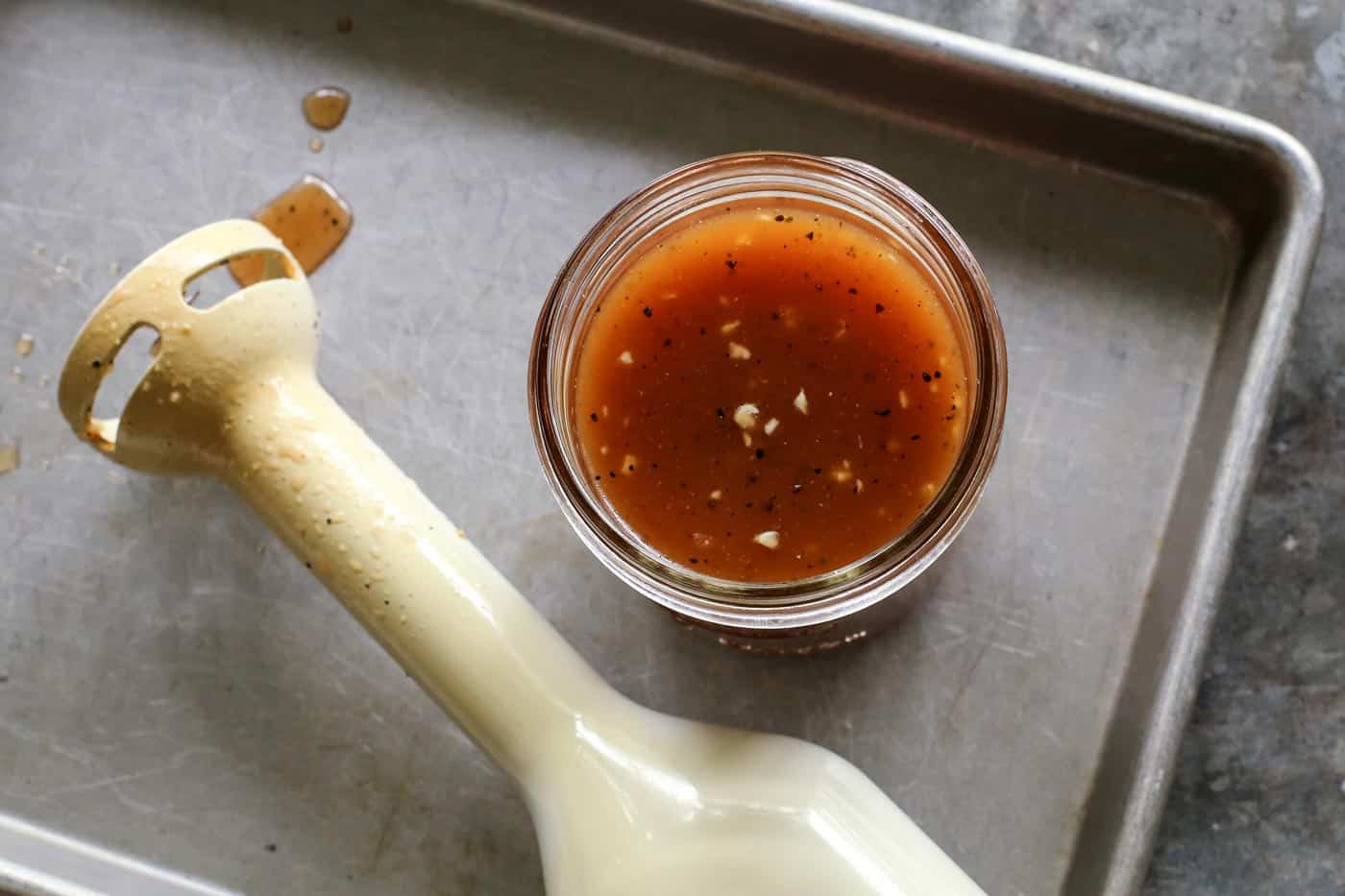 This simple sweet red wine vinaigrette is an easy homemade salad dressing that uses just a few pantry items and takes only 5 minutes to make! jar of red wine vinaigrette salad dressing and an immersion blender on a pan