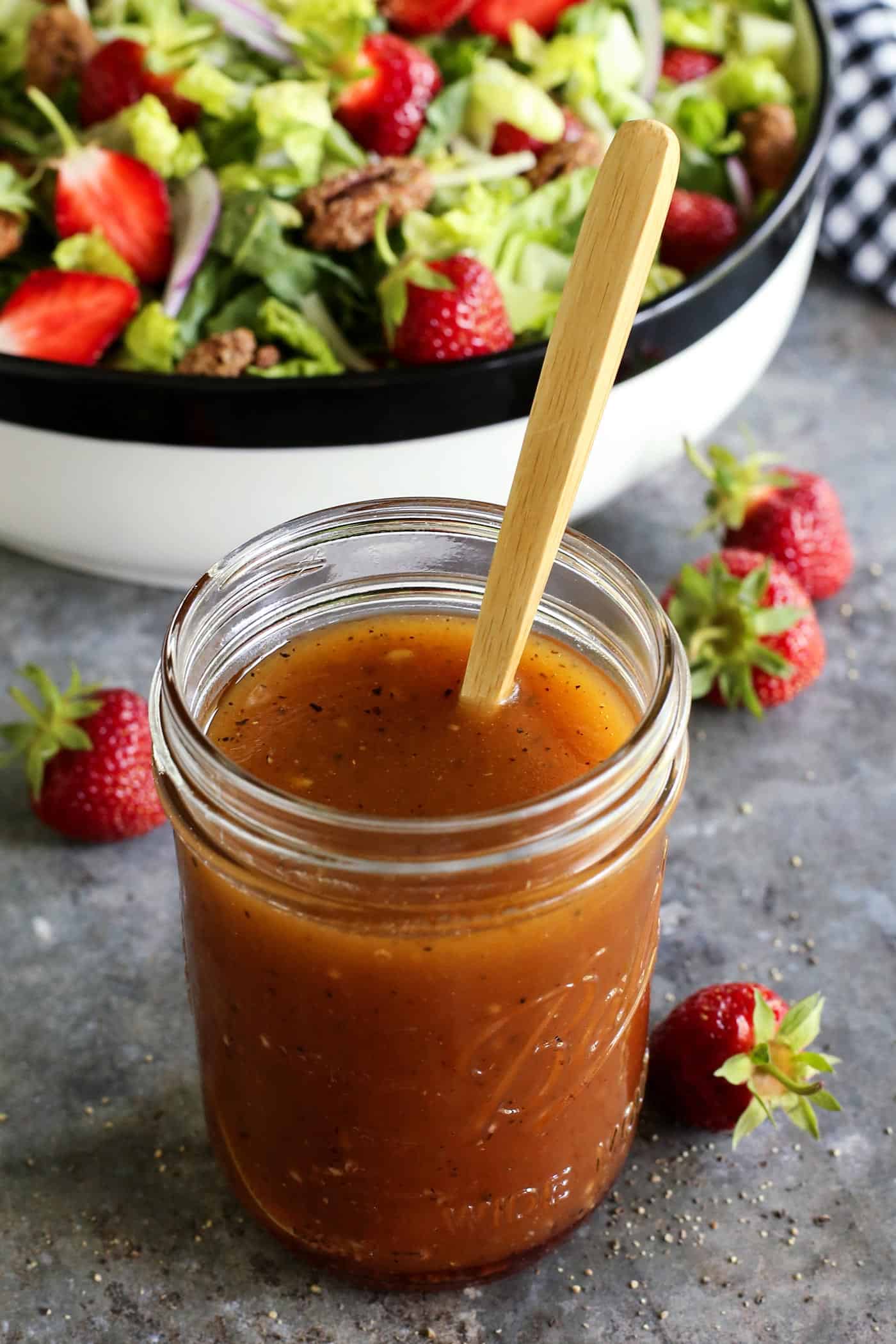 This simple sweet red wine vinaigrette is an easy homemade salad dressing that uses just a few pantry items and takes only 5 minutes to make! red wine vinaigrette dressing in a jar, with a salad in the background